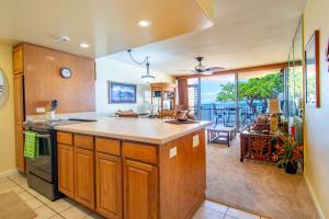 una cucina con armadi in legno e vista su un balcone di Kahana Reef 208 a Kahana