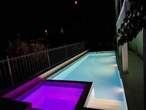 a swimming pool at night with purple lights at Apartments Neli in Vinišće