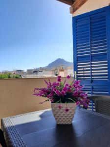un jarrón con flores púrpuras sentado en una mesa en Turismo Egadi - Appartamenti, en Favignana