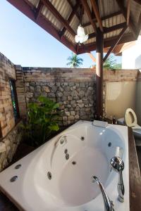 a bath tub in a bathroom with a stone wall at Phangan Paragon Resort & Spa by Pure Lifestyle in Haad Chao Phao