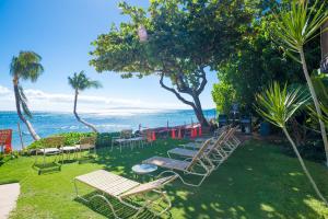 a yard with chairs and tables and the ocean at Hono Kai B15 in Maalaea