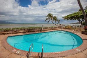 a swimming pool with the ocean in the background at Hono Kai B15 in Maalaea