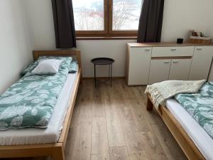 a bedroom with two beds and a table and a window at Chata Pod Skalkami in Vyšný Kubín