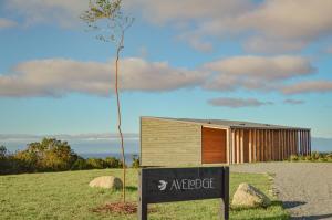 een boom met een bord voor een gebouw bij Ave Lodge Frutillar in Frutillar