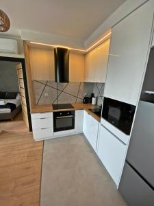 uma cozinha com armários brancos e um fogão preto em Ogrodowa70 Apartment em Sztutowo