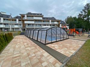 uma ponte de metal sobre uma piscina com parque infantil em Ogrodowa70 Apartment em Sztutowo