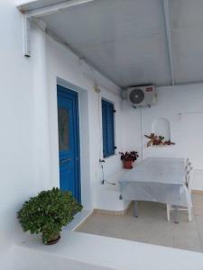 Habitación blanca con mesa y puerta azul en Peaceful and quiet apartment., en Aliki