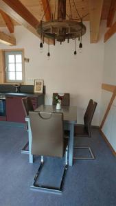 a dining room with a table and chairs and a chandelier at Mothsgut - moderne Ferienwohnung auf dem Bauernhof im Erzgebirge in Oelsnitz