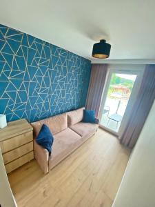 a living room with a couch and a blue wall at Ogrodowa70 Apartment in Sztutowo