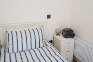 a bed with a striped pillow and a night stand at Tranquil Rustic Cottage in Dromore