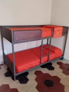 Bilocale per vacanze a Vada في فادا: سرير بطابقين احمر في غرفة مع ارضية
