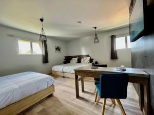 1 dormitorio con 2 camas, mesa y 1 cama en Hôtel En Tilleul en Pont-du-Navoy