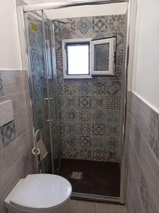 uma casa de banho com um chuveiro, um WC e uma janela. em Bilocale per vacanze a Vada em Vada