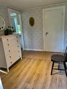 an empty living room with a dresser and a chair at Litet hus på landet 