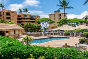 a pool with chairs and umbrellas in a resort at Kahana Villa E111 in Kahana