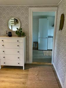 uma cozinha com uma cómoda branca e um espelho em Litet hus på landet 