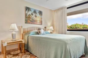 a bedroom with a bed and a window with palm trees at Kamaole Sands 8-201 in Wailea