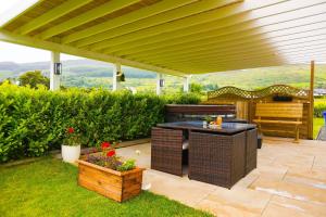 a patio with a table and a bench under a pergola at Clonlum Holiday Cottages in Newry