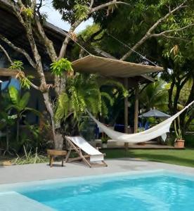 una hamaca y una silla junto a la piscina en Lá em Casa - Guest House, en Barra Grande
