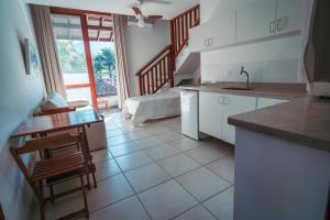 a kitchen with white cabinets and a table and chairs at Vila Bardot in Barra do Sahy