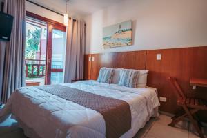 a hotel room with a bed and a balcony at Vila Bardot in Barra do Sahy