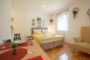 a bedroom with a bed and a table and a couch at Studio Sunlight+ private parking in Novi Sad