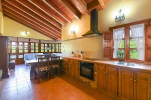 cocina con armarios de madera, mesa y comedor en Apartamentos Rurales El Cuetu, en Picones