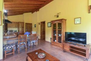 a living room with a large television and a kitchen at Apartamentos Rurales El Cuetu in Picones