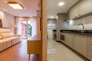een keuken en een woonkamer met een bank bij Rosa Edifício Reservas das Orquídeas in Gramado
