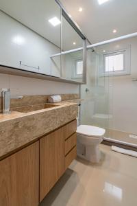 een badkamer met toilet en glazen douche bij Rosa Edifício Reservas das Orquídeas in Gramado +47 foto's