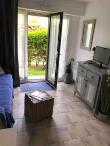 Una sala de estar con suelo de baldosas y una puerta corrediza de vidrio. en Le Clapotis des Flots, en Villers-sur-Mer