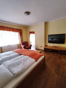 a bedroom with a large bed and a flat screen tv at Chata Gatterhof in Banská Štiavnica