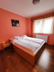 a bedroom with orange walls and a bed with white sheets at Chata Gatterhof in Banská Štiavnica