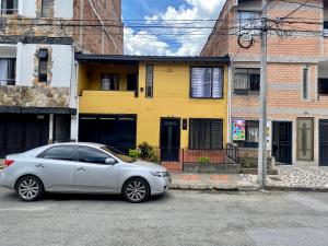 un coche plateado estacionado frente a una casa amarilla en CASA FAMILIAR AMPLIA MUY FRESCA en Medellín