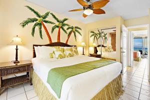 a bedroom with a large bed and palm trees at Hololani A203 in Kahana +20 photos