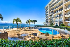 a resort with a swimming pool and chairs and a building at Hololani A203 in Kahana