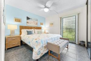 a bedroom with a bed and a chair and a window at Kihei Akahi B102 in Wailea