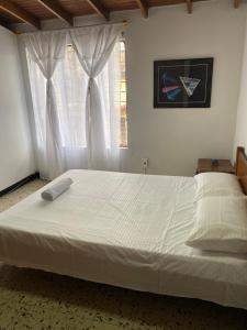 Schlafzimmer mit einem großen weißen Bett und einem Fenster in der Unterkunft CASA FAMILIAR AMPLIA MUY FRESCA in Medellín