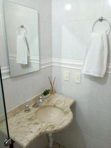 y baño con lavabo de mármol y espejo. en Apartamento Solar da Borges, en Gramado