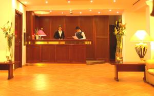 Hotel Moderno في أولبيا: شخصين واقفين في مكتب استقبال في بهو الفندق
