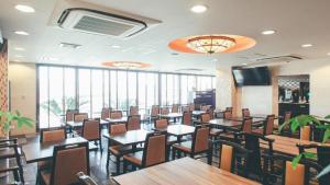 a dining room with tables and chairs and windows at Kuretake-Inn Kikugawa I.C. in Kikugawa