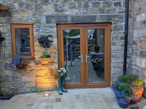 ein Steingebäude mit einer Holztür, in der eine Person ein Bild macht in der Unterkunft Charming 1-Bed Cottage on the outskirts of Haworth in Keighley