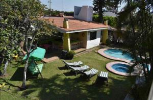 une arrière-cour avec une piscine, des chaises et une maison dans l'établissement La Manzana de Raquel, à Oaxtepec