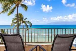 two chairs sitting on a balcony overlooking the beach at Paki Maui 405 in Honokowai