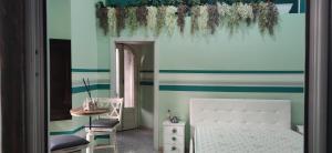 ein Schlafzimmer mit einem weißen Bett und einer blau-grünen Wand in der Unterkunft Room Rome in Roccella Ionica
