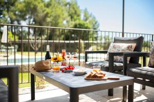 una mesa con comida y vino en el balcón en Bastide Toujours Dimanche, Maison de vacances avec vue & piscine privée, en Gordes