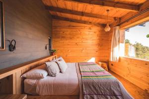 um quarto com uma cama num chalé de madeira em Casita boutique con tina exterior em Pichilemu