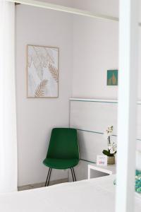 a green chair in a room with a white wall at Hotel Flora in Cattolica