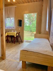 una camera da letto in una cabina di legno con un letto e un tavolo di Zem Priedēm a Lapmežciems