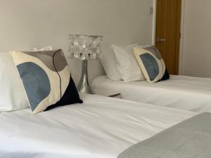 a bedroom with two beds with pillows and a lamp at Villa Levante in Paignton
